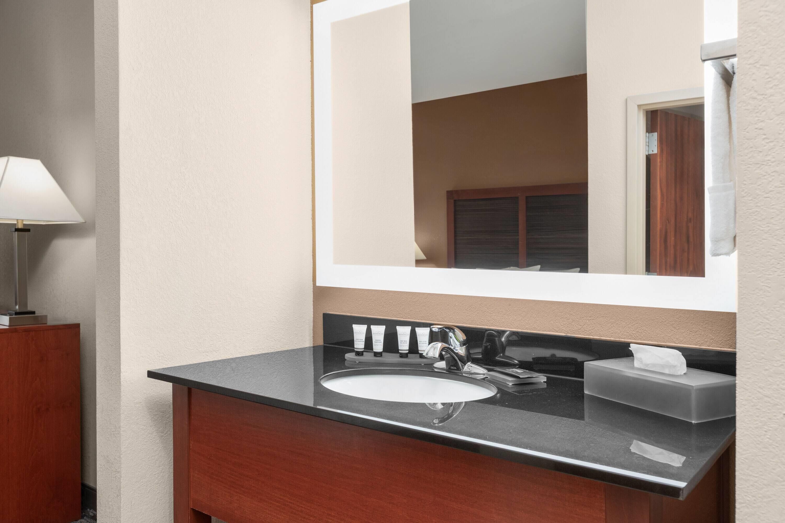 Une salle de bain équipée d’un lavabo, d’un miroir et d’articles de toilette.