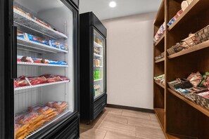 Un présentoir réfrigéré contenant divers produits alimentaires et une étagère en bois sur laquelle sont disposés des produits emballés.