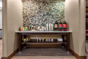 Una zona de bar con protección de mármol, máquinas de café y diversos utensilios.
