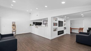 Amplia sala de estar con piso de madera, una mesa de recepción, un televisor y una estantería.