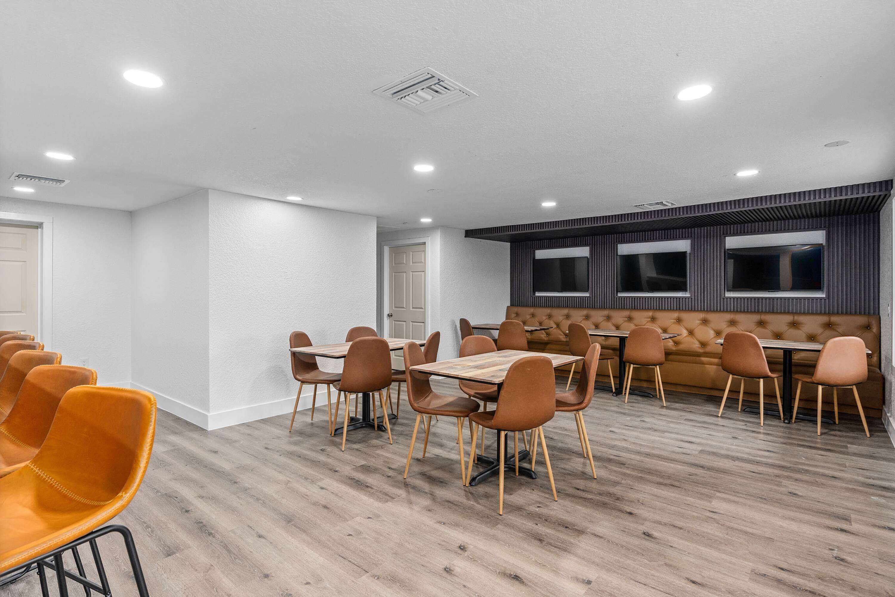 A conference room with a long table, multiple chairs, a sofa, and large windows.