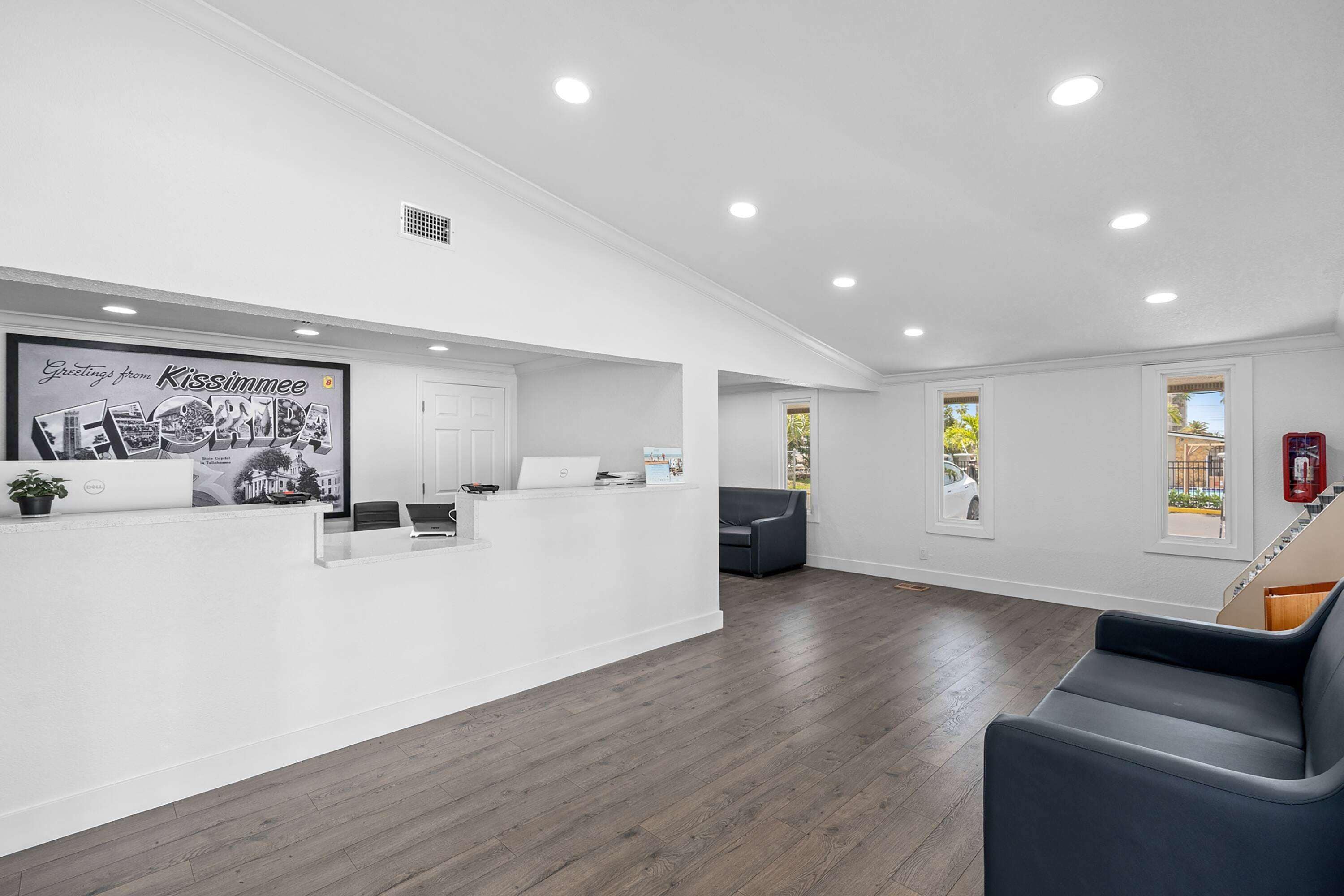 A reception area with a white desk, a laptop, and a framed photo on the wall.