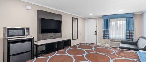 Una habitación de hotel con una cama, un escritorio con microondas, televisión y una silla.