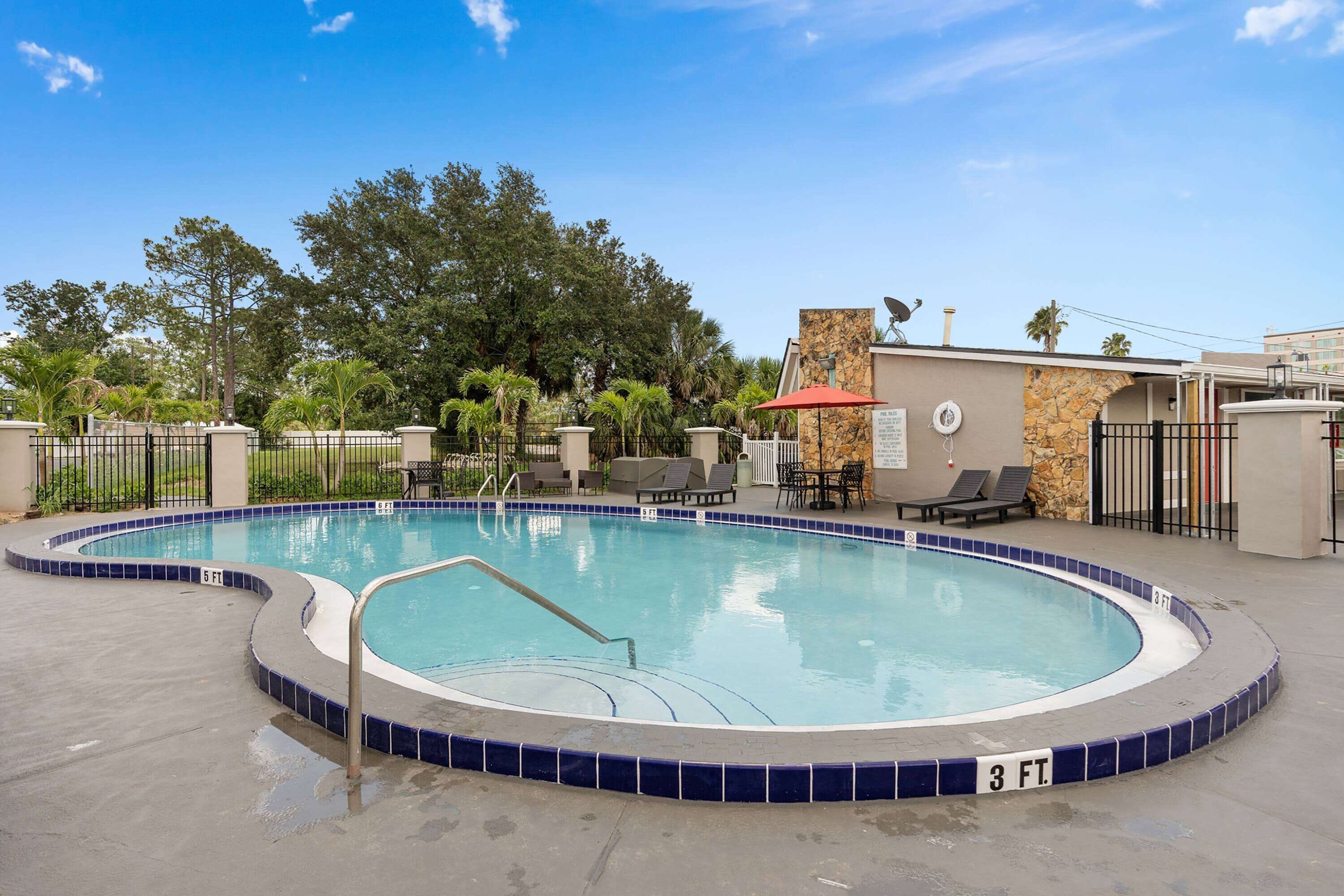 A swimming pool with a 3 FT safety zone, surrounded by lounge chairs and a stone wall.