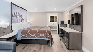 Una habitación de hotel moderna con una cama grande, un escritorio, un televisor y un baño visible a través de una puerta abierta.