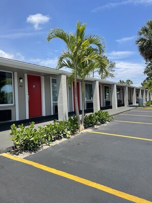 A row of motel rooms with red doors, numbered 202 and 205, and a parking lot with yellow lines. - Super 8 by Wyndham Kissimmee/Orlando (Kissimmee)