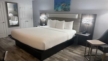 A modern bedroom with a large bed, a bedside table, a chair, and a mirror.