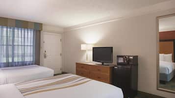 Quarto de hotel com duas camas, televisão, micro-ondas, cómoda e um espelho grande.