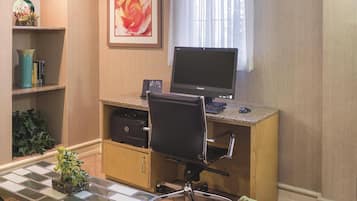 A home office with a desk, computer, chair, and shelves with books and plants.