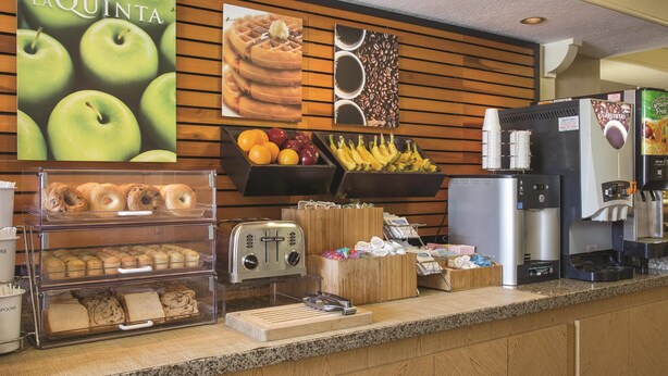 Una barra de desayuno con la marca La Quinta, una máquina de café y una exhibición de gofres.