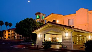Un hotel con una destacada torre de campanas, un acceso cubierto y una fachada bien iluminada.