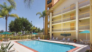 Un hotel con piscina, mobiliario exterior y palmeras.