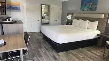A hotel room with a bed, desk, chair, and a large mirror.