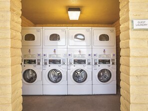 A row of stacked laundry machines with a sign indicating 'Guest Laundry'.