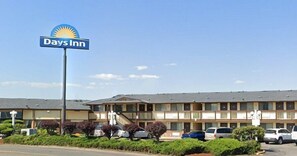 A Days Inn hotel with a sign, a parking lot, and a building with multiple floors and balconies. - Days Inn by Wyndham Auburn (Auburn)