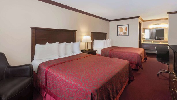 A hotel room with two beds, a desk, a chair, and a mirror. - Days Inn by Wyndham Auburn (Auburn)