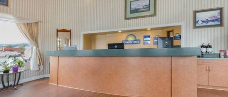 A reception desk with a Days Inn sign, a framed picture, and a window with curtains.
