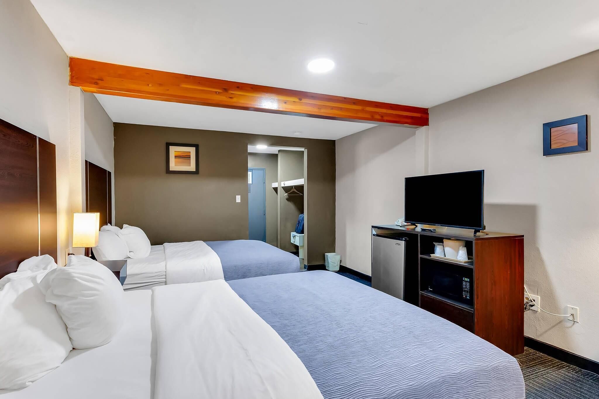 Une chambre d’hôtel avec deux lits, une télévision, un bureau et une armoire.