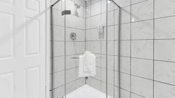 Une salle de bain moderne avec une douche à parois de verre, des carreaux de marbre blanc et une serviette blanche suspendue à un porte-serviettes.