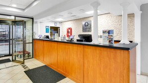 A hotel reception area with a wooden counter, a glass door entrance, a fire extinguisher, and a sign indicating 'Quality by Choice Hotels'. - Quality Inn Salisbury North (Salisbury)