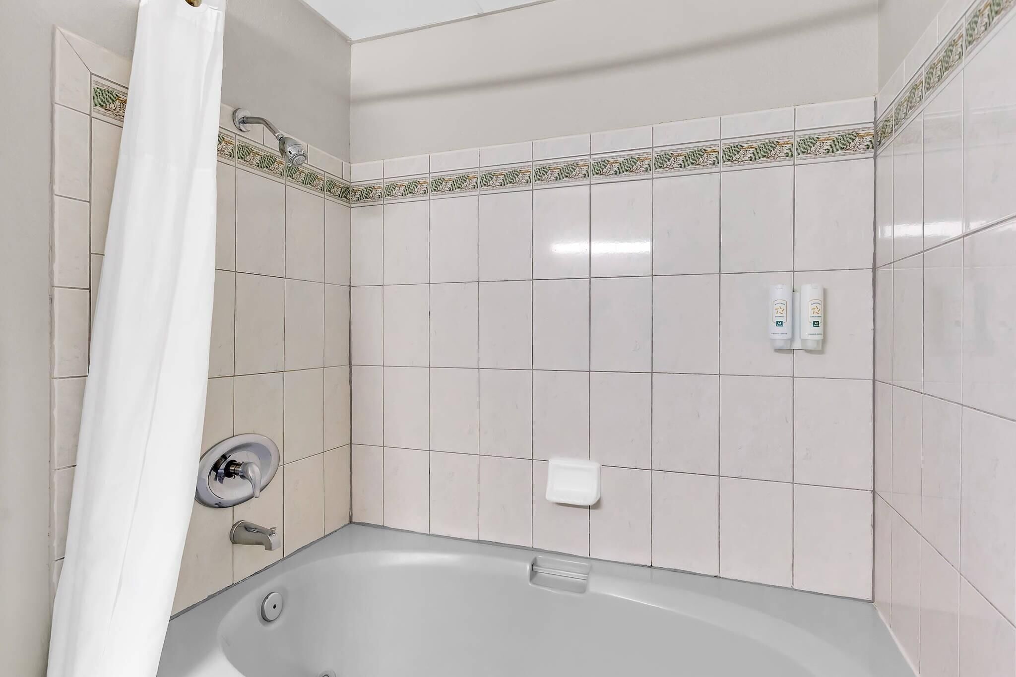 A bathroom with a bathtub, a shower curtain, and tiled walls.