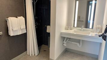 A modern bathroom with a shower, a sink, and a mirror.