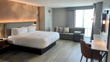 Una habitación de hotel moderna con una cama grande, un sofá, un escritorio y un televisor.