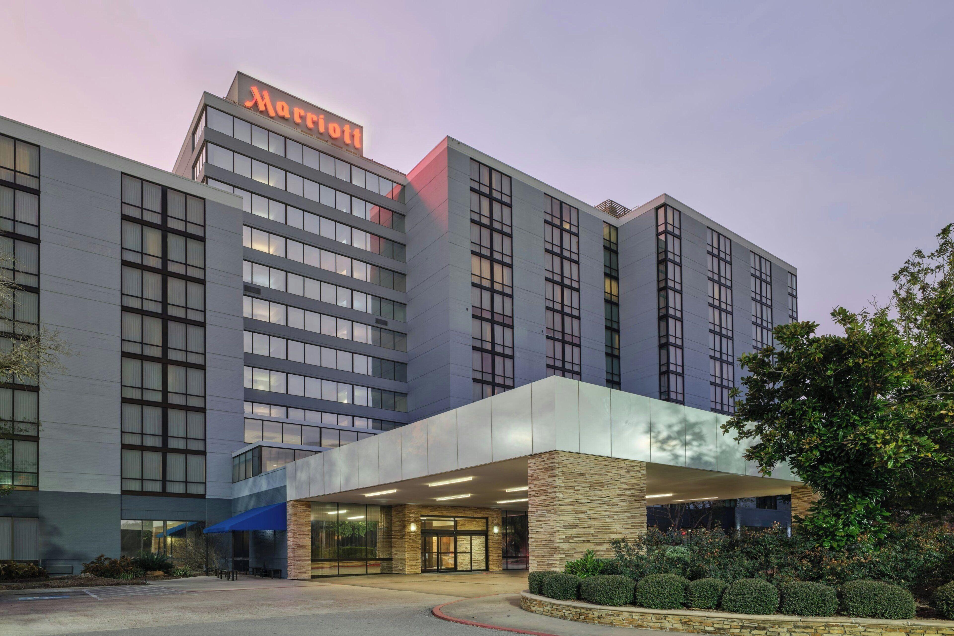 Un hotel Marriott con una fachada moderna, ventanas amplias y una entrada bien iluminada.