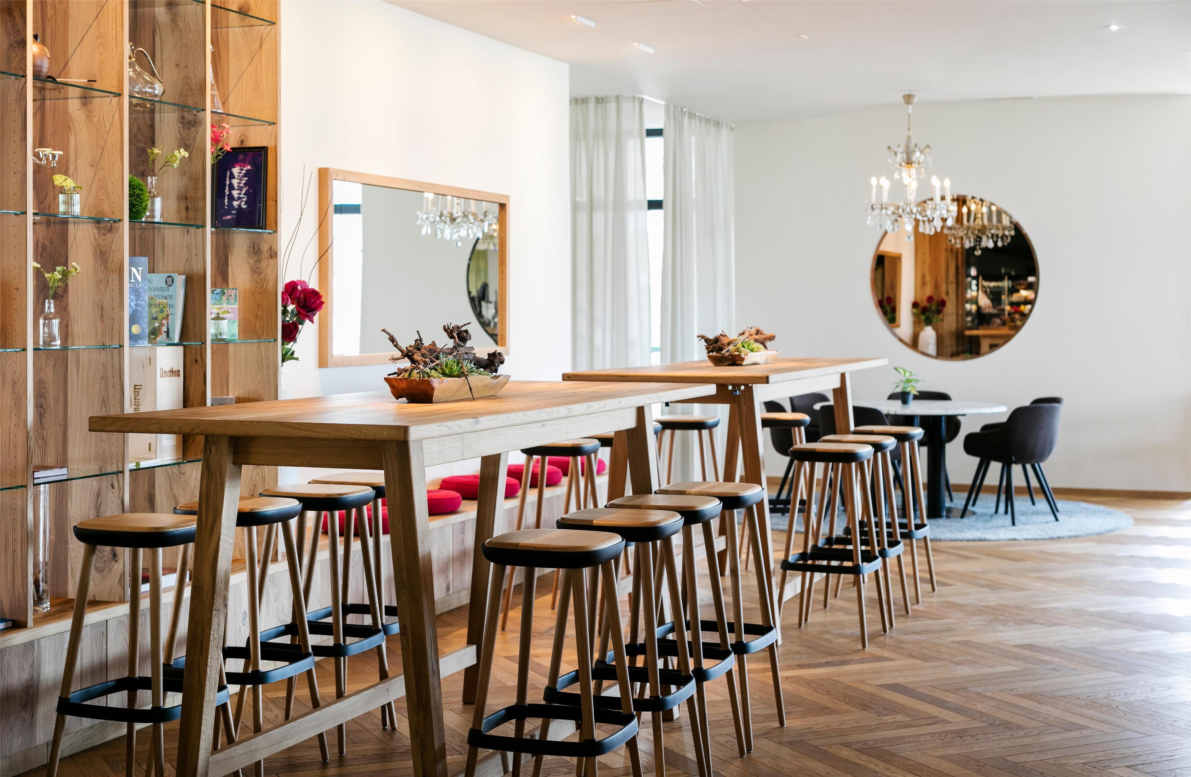 A modern bar area with wooden stools, a long counter, and a mirror.