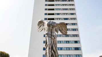 A tall building with a prominent statue of a winged figure at its base.