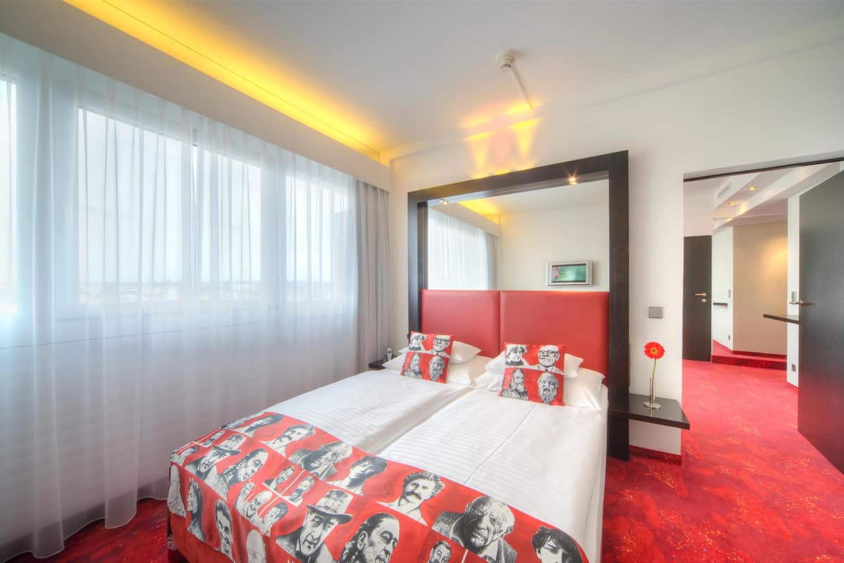 A hotel room with a large bed, a mirror, and a red carpet.
