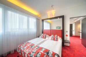 A hotel room with a large bed, a mirror, and a red carpet.