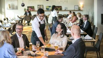 A restaurant with multiple tables, waitstaff, and diners.
