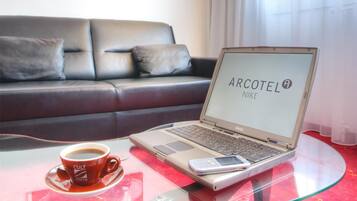 Ein modernes Zimmer mit Glastisch, Laptop, Kaffeetasse und einer Couch.