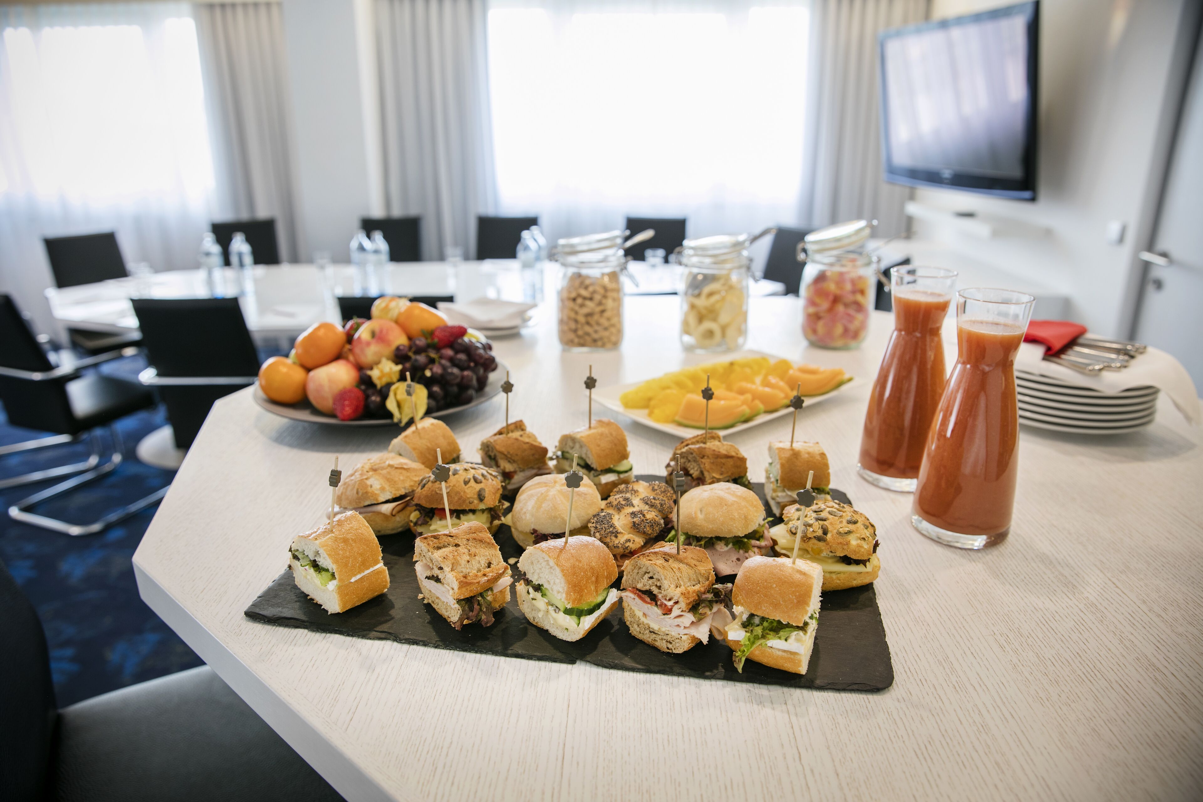 A buffet table with sandwiches, fruits, and beverages.