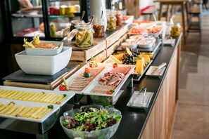 A buffet with various food items including meats, cheeses, and salads.