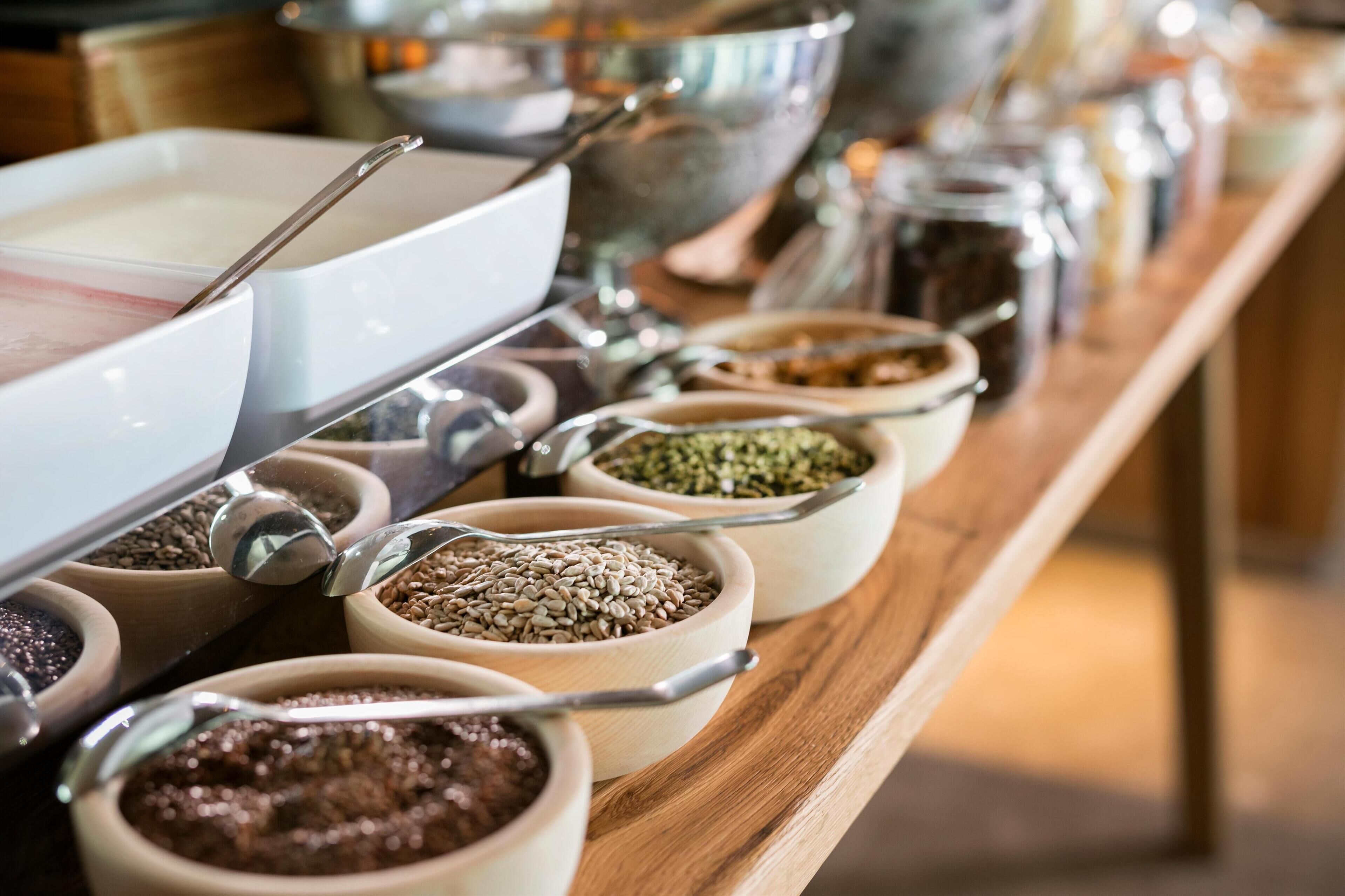 A buffet with various food items in bowls and a large white bowl with a spoon.