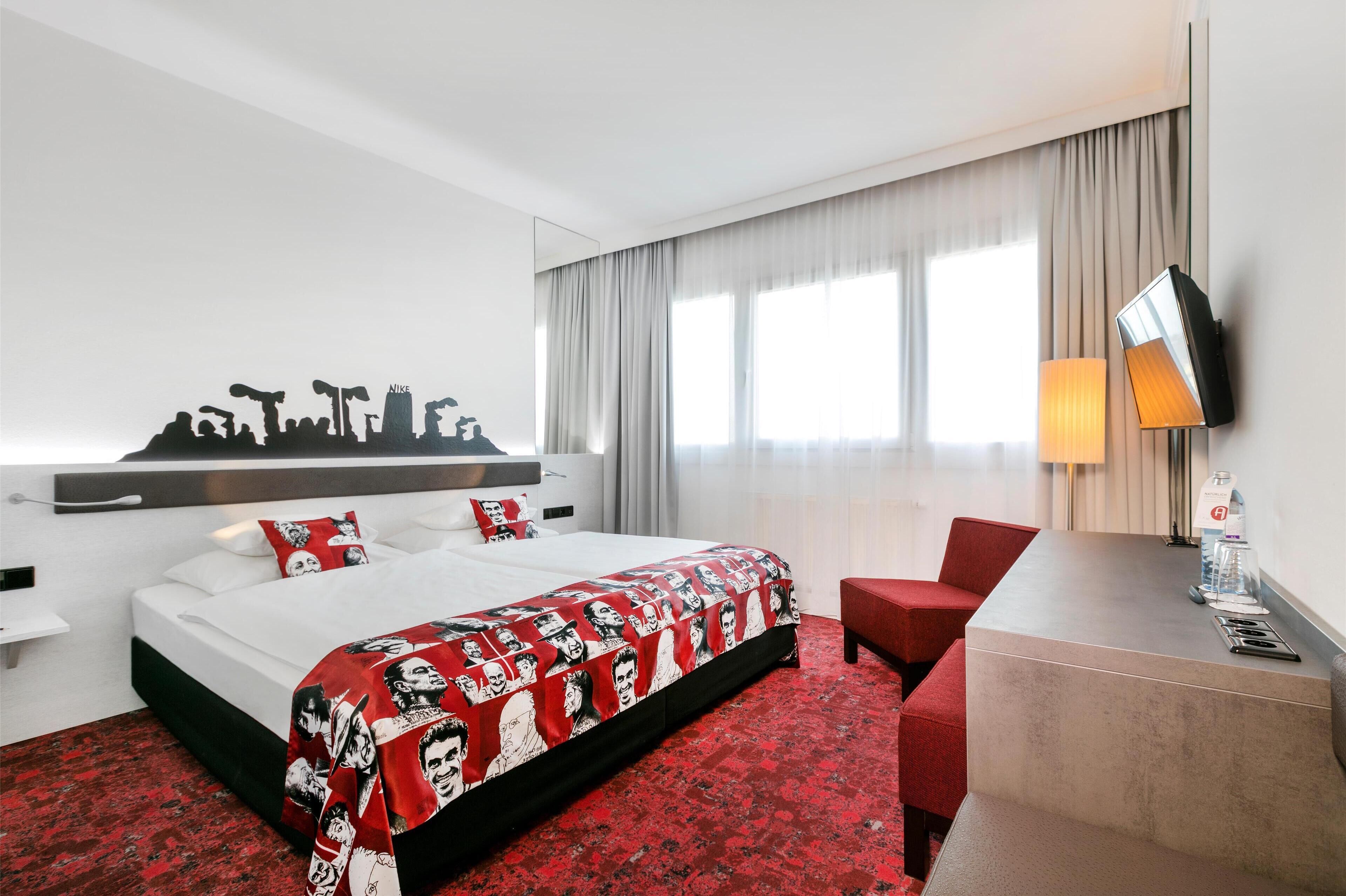 A hotel room with a bed, a desk, a chair, and a large window with curtains.