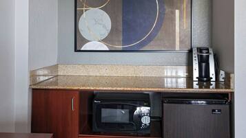 A compact kitchenette with a microwave, coffee maker, and refrigerator.