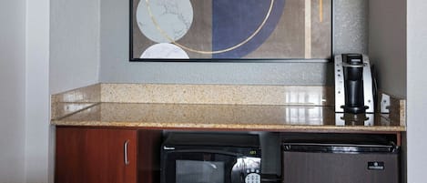 A compact kitchenette with a microwave, coffee maker, and refrigerator.