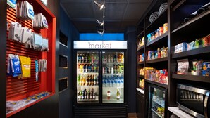 A narrow aisle with a refrigerated display case labeled "the market" on the left, stocked with beverages and snacks. - Courtyard by Marriott San Antonio Airport (San Antonio)