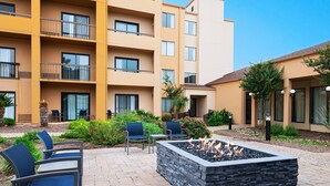 A courtyard with outdoor seating, a fire pit, and a multi-story building with balconies. - Courtyard by Marriott San Antonio Airport (San Antonio)