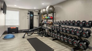 A gym with a bench, dumbbells, medicine balls, and a stationary bike. - Hampton Inn Kansas City-Airport (Kansas City)