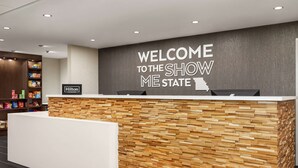 A reception desk with a wooden wall design, a sign reading "WELCOME TO THE SHOW ME STATE", and a "Hilton Honors" sign. - Hampton Inn Kansas City-Airport (Kansas City)