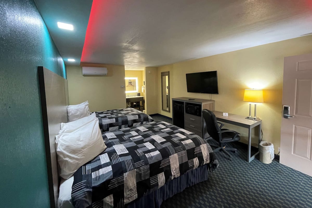 Ein Hotelzimmer mit Bett, Schreibtisch, Stuhl, Fernseher und Lampe.