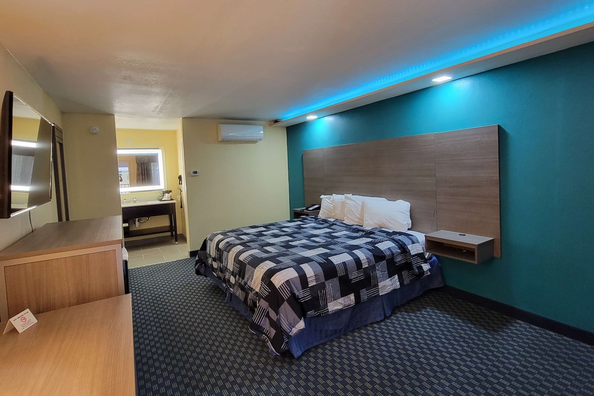 Ein Hotelzimmer mit Bett, Schreibtisch, Spiegel und Klimaanlage.