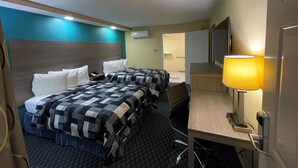 Een hotelkamer met twee bedden, een bureau, een stoel, een lamp, een televisie en een airconditioningsunit.