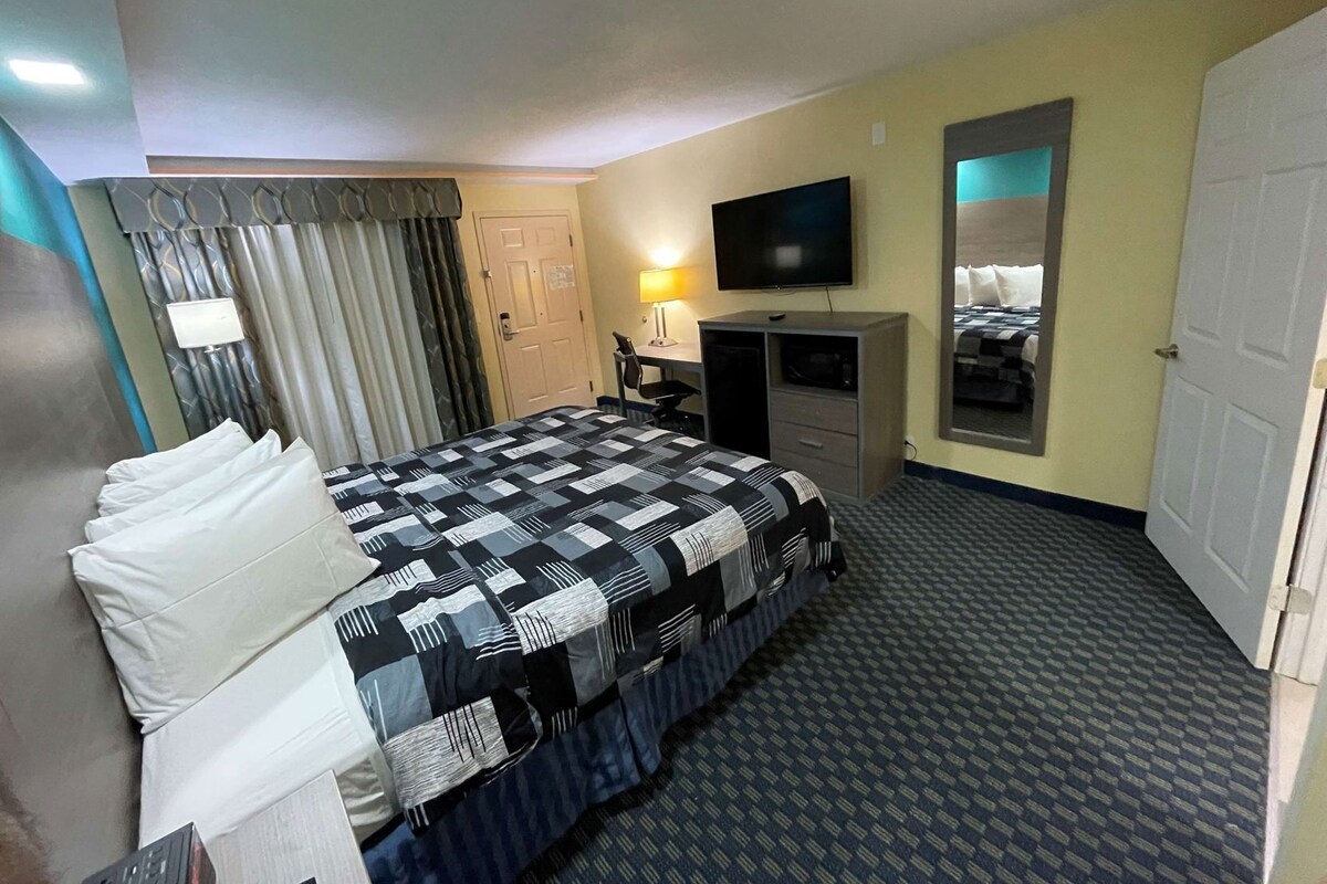 A hotel room with a bed, a desk, a television, and a mirror.