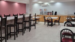 Een restaurant met marmeren vloertegels, houten stoelen en een toonbank met koffieapparatuur.