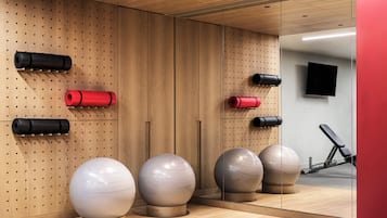 Ett gym med träningsbollar, yogamattor och en tv på väggen.